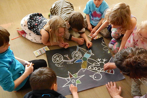 A group of young learners huddled around a drawing