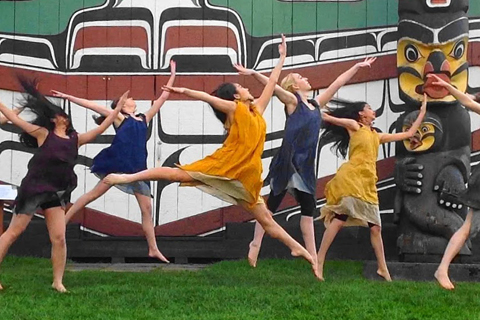 A group of artists dancing in front of a mural